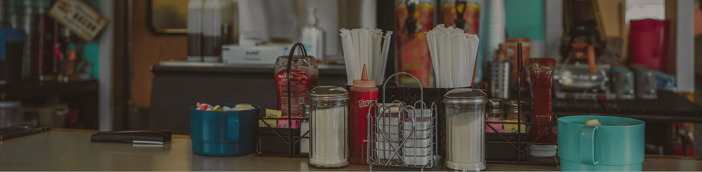 Diner table with different items such as straws, salt, pepper, etc